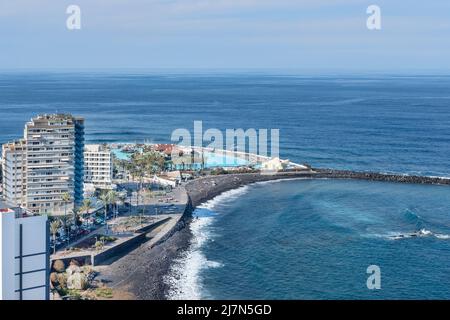 Blick von Mirador de la Paz auf die charmante Stadt mit Hotels, einem schwarzen Sandstrand und dem Wasserpark Lago Martianez, Puerto de la Cruz Stockfoto