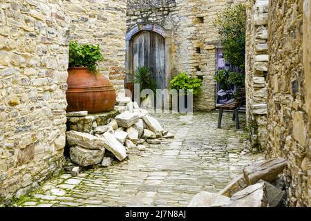 Traditioneller idyllischer Hof in einem Bergdorf in Zypern mit großen alten Terrakotta-Amphoren-Weinkellern, die als Blumentopf verwendet werden Stockfoto