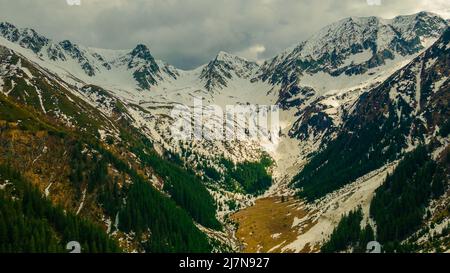 Panoramablick auf die Karpaten im Frühling, mit schneebedeckten Gipfeln. Die Fotografie wurde von einer Drohne in einer höheren Höhe aufgenommen. Stockfoto