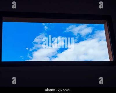 Blauer Himmel mit Wolken durch ein Fenster Stockfoto