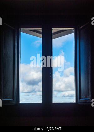 Blauer Himmel mit Wolken durch ein Fenster Stockfoto