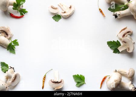 Rahmen aus frischem Pilz, Petersilie, Gewürz auf weißem Hintergrund. Champignonpilz. Gesundes Lebensmittelkonzept. Direkt darüber. Speicherplatz kopieren. Stockfoto