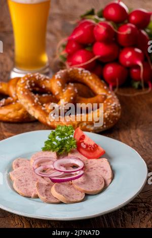 bayerischer Wurstsalat auf dunklem Holz Stockfoto