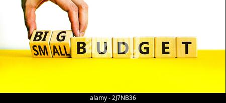 Großes oder kleines Budgetsymbol. Geschäftsmann dreht Holzwürfel und ändert Wörter kleines Budget zu großes Budget. Schöne gelbe Tabelle weißen Hintergrund, Kopie Stockfoto