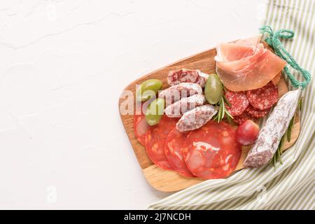 Verschiedene Fleischsnacks, Wurstplatte mit verschiedenen Wurstsorten - Salami, bresaola, Proscuitto serviert mit Oliven, Rosmarin und frischer Traube Stockfoto