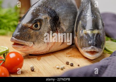 Frischer dorado-Fisch, auf einem Holzbrett, zwei Köpfe aus der Nähe. Stockfoto