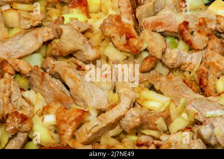 Schweinefleisch und gehackte weiße Zwiebel, in einer heißen Pfanne mit Öl gebraten, Nahaufnahme. Stockfoto