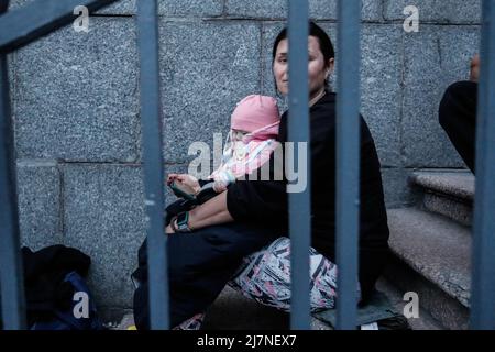 Dnipro, Dnipro, Ukraine. 10.. Mai 2022. Eine ukrainische Mutter, die ihre Tochter in die Arme streckt, sitzt auf der Treppe, während sie auf den Zug nach Lemberg wartet, in der Hoffnung, nach Polen zu fliehen, während die russische Invasion der Ukraine weitergeht. (Bild: © Daniel Ceng Shou-Yi/ZUMA Press Wire) Stockfoto