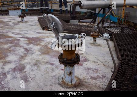 Junger Offshore-Ingenieur, der auf dem Frachtdeck des Versorgungsschiffs im Hafen den Tank für Heizöl sondgt Stockfoto