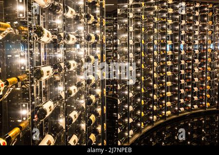 Eine Wand aus Weinflaschen verschiedener Art in einer gebogenen Glaswand, die für eine Wiederholung von Abtrakt / Hintergrund-Muster in die Ferne Stockfoto