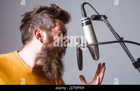 Bärtiger Mann in Karaoke. Guy singt im Kondensatormikrofon. Professionelle Sängerin in Studio Records. Stockfoto