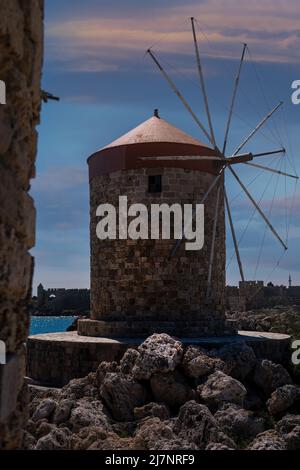 Windmühlen im Mandraki Hafen bei Sonnenuntergang. Stockfoto