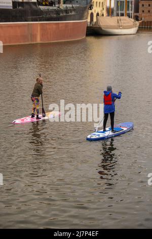 Danzig Polen März 2022 Gruppe von Sup-Surfern stehen auf Paddle-Board, Frauen stehen auf Paddeln zusammen in der Stadt Motlawa Fluss und Kanal in der Altstadt Danzig Polen. Tourismusattraktion Aktive Erholung im Freien Soziale Distanzierung Reiseziele Stockfoto