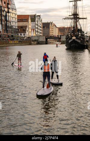 Danzig Polen März 2022 Gruppe von Sup-Surfern stehen auf Paddle-Board, Frauen stehen auf Paddeln zusammen in der Stadt Motlawa Fluss und Kanal in der Altstadt Danzig Polen. Tourismusattraktion Aktive Erholung im Freien Soziale Distanzierung Reiseziele Stockfoto