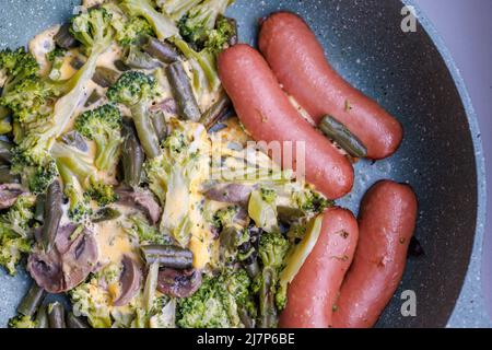 Gebratene Würstchen und Gemüse mit Pilzen und Hühnereier auf einer Pfanne Stockfoto