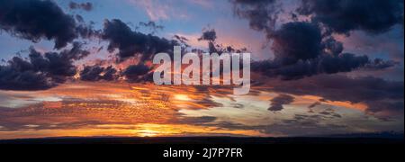 Ein Sonnenaufgang malt die Wolken jede Farbe des Regenbogens in Ebenen von Stockfoto