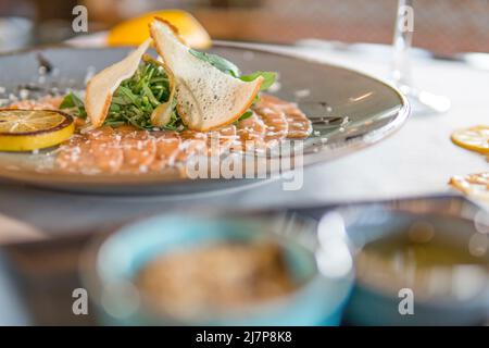 Lachs-Carpacio mit Brotscheiben und Zitrone Stockfoto