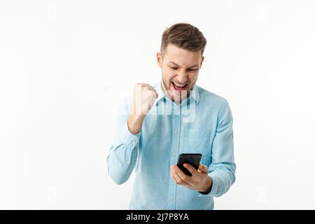 Ein Geschäftsmann hält ein Smartphone und freut sich über eine erfolgreiche Transaktion. Telearbeit, freiberuflich. Stockfoto