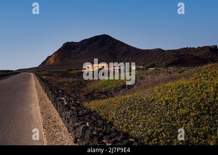 Straße mit Trockensteinmauer . Der Vulkan Monte Nero im Hintergrund. Linosa, Sizilien Stockfoto