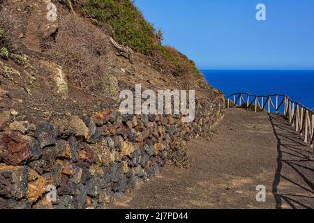 Weg zum Vulkan Monte Nero von Linosa. Charakteristische Landstraße mit der Trockensteinmauer, die aus Lavasteinen gebaut wurde Stockfoto