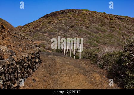 Weg zum Vulkan Monte Nero von Linosa. Charakteristische Landstraße mit der Trockensteinmauer, die aus Lavasteinen gebaut wurde Stockfoto