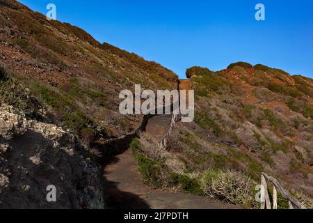 Weg zum Vulkan Monte Nero von Linosa. Charakteristische Landstraße mit der Trockensteinmauer, die aus Lavasteinen gebaut wurde Stockfoto