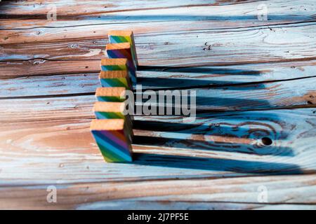 Dominosteine mit farbenfrohem Druck, die auf einen Holztisch gefallen sind Stockfoto