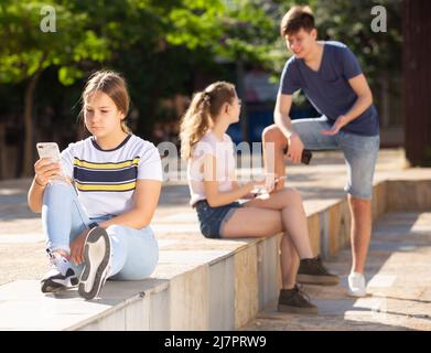 Teenager spielen auf dem Smartphone auf der Straße Stockfoto