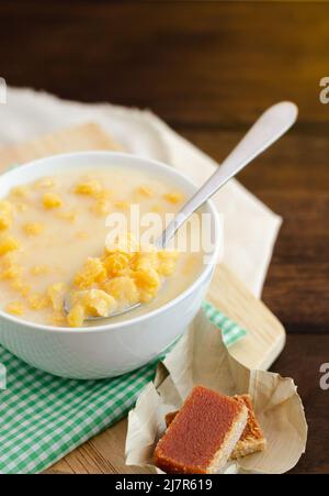 Traditionelles kolumbianisches Essen namens Mazamorra, basierend auf gekochtem Mais, der in Milch aufgelöst wurde, begleitet von süßem Guava (genannt Bocadillo). Dunkler Hintergrund. Stockfoto