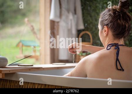 Eine Frau im Whirlpool, die sich mit Wasser übergießt Stockfoto