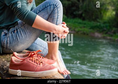 Nahaufnahme von Frauenfüßen und -Schuhen in der Nähe des Flusses Stockfoto