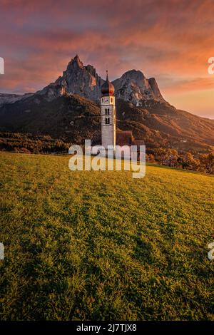 Seis am Schlern, Italien - wunderschöner Sonnenuntergang und idyllische Bergkulisse in den italienischen Dolomiten mit St. Valentin Kirche und dem berühmten Schlern mit Stockfoto