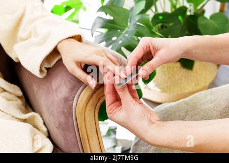 Crop anonymen Meister mit Nagelfeile Sägen Nägel von unkenntlich weiblichen Client sitzt im Sessel während der Vereinbarung im Schönheitssalon Stockfoto