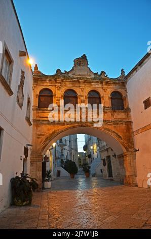 Eine Familie geht nachts in Ostuni, Apulien, Italien, eine Straße entlang Stockfoto