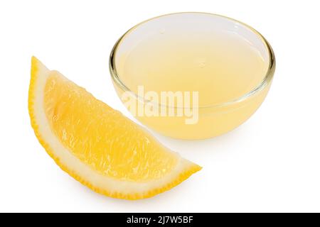 Frisch gepresster Zitronensaft in einer Glasschüssel neben dem Zitronensegment, isoliert auf Weiß. Stockfoto