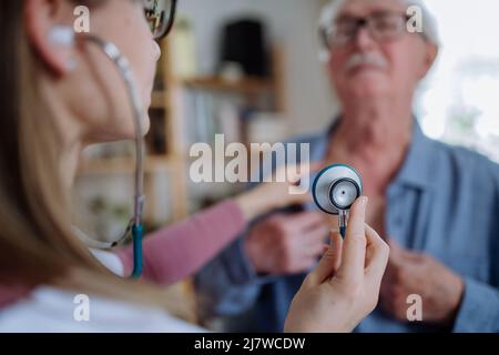 Ärztin besucht einen älteren Mann und untersucht ihn zuhause. Stockfoto