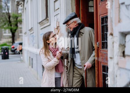 Erwachsene Tochter, die ihren älteren Mann zu einem Spaziergang in der Stadt mitnimmt. Stockfoto