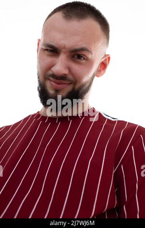 Vertikales Bild von unrasierten lächelnden Mann Gesicht, Grimassen und Blick auf die Kamera, mit Borsten. Augenbraue ironisch anheben Stockfoto