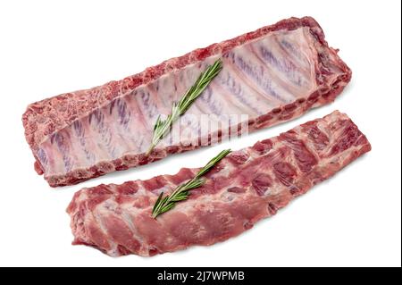 Rohe Schweineribs mit Rosmarin auf Weiß isoliert. Rohe Schweineribs servierten Rosmarin zum Kochen. Rohes Fleisch, ganze Schweinerippen. Rohes Schweinefleisch Spare Ribs oder Bauch Stockfoto