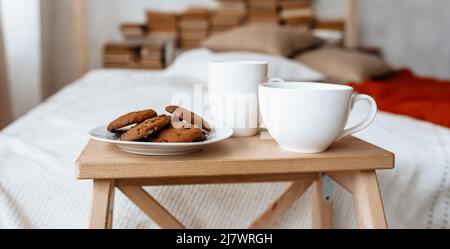 Frühstück im Bett. Heißer Kaffee mit Haferflocken und Schokolade auf einem Holztablett Stockfoto