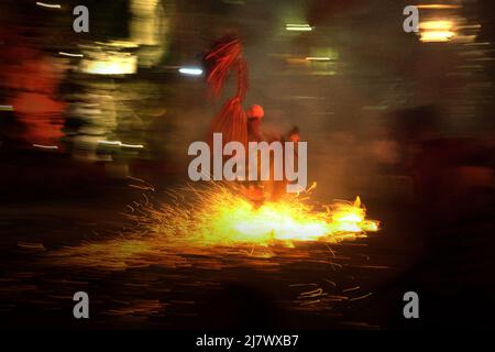 Ein Feuertanz-Darsteller läuft während der Kecak- und Feuertanz-Show in Ubud, Gianyar, Bali, Indonesien über einen Haufen brennender Kokosnüsse. Stockfoto