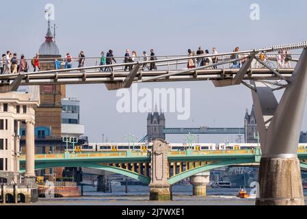 Menschen, die über die Millennium Bridge in London, Großbritannien, über die Southwark Bridge, die Cannon Street Bahnhofsbrücke und den Zug und die Tower Bridge laufen Stockfoto