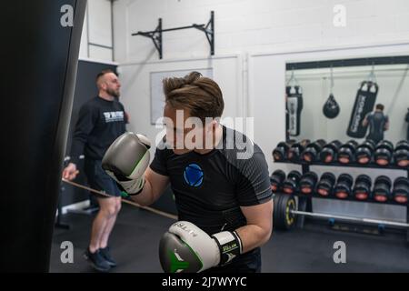 Ipswich Suffolk UK April 03 2022: Ein junger Sportler, der ein Boxtraining im Fitnessstudio macht, ein Kerl, der Boxsack boxt Stockfoto