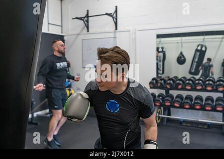 Ipswich Suffolk UK April 03 2022: Ein junger Sportler, der ein Boxtraining im Fitnessstudio macht, ein Kerl, der Boxsack boxt Stockfoto