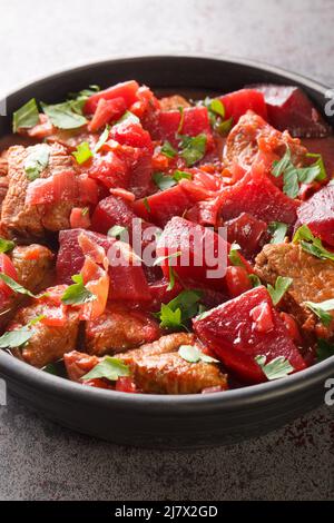 Geschmortes Rindfleisch mit Rüben und Zwiebeln in einer würzigen Sauce in einer Schüssel auf dem Tisch. Vertikal Stockfoto
