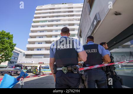 Hanau, Deutschland. 11.. Mai 2022. Polizeibeamte stehen vor einem Hochhaus in der Innenstadt von Hanau, wo am Morgen ein totes Mädchen gefunden wurde. Vor dem Haus lag ein schwer verletzter Junge auf der Straße. Kredit: Frank Rumpenhorst/dpa/Alamy Live Nachrichten Stockfoto