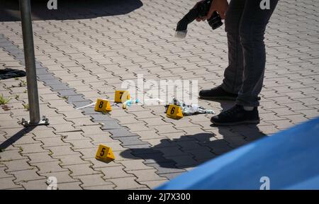 Hanau, Deutschland. 11.. Mai 2022. Forensiker arbeiten auf dem Platz vor einem Hochhaus in der Innenstadt von Hanau, wo heute Morgen ein totes Mädchen gefunden wurde. Vor dem Haus lag ein schwer verletzter Junge auf der Straße. Kredit: Frank Rumpenhorst/dpa/Alamy Live Nachrichten Stockfoto