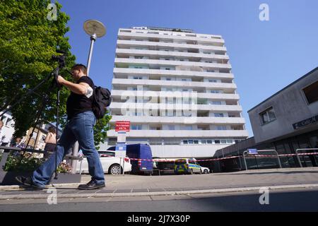 Hanau, Deutschland. 11.. Mai 2022. Vor einem Hochhaus in der Innenstadt von Hanau, wo heute Morgen ein totes Mädchen gefunden wurde, hängt eine Polizeischnur. Vor dem Haus lag ein schwer verletzter Junge auf der Straße. Kredit: Frank Rumpenhorst/dpa/Alamy Live Nachrichten Stockfoto