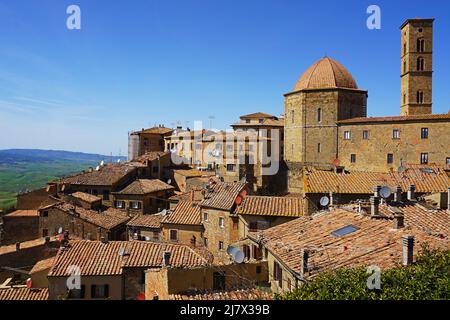 Traditionelle alte Häuser und Dächer aus Stein und Backstein mit blauem Himmel in Volterra, Toskana Stockfoto