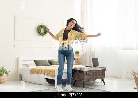 Aufgeregte Dame, die zu Hause Musik hört und tanzt Stockfoto